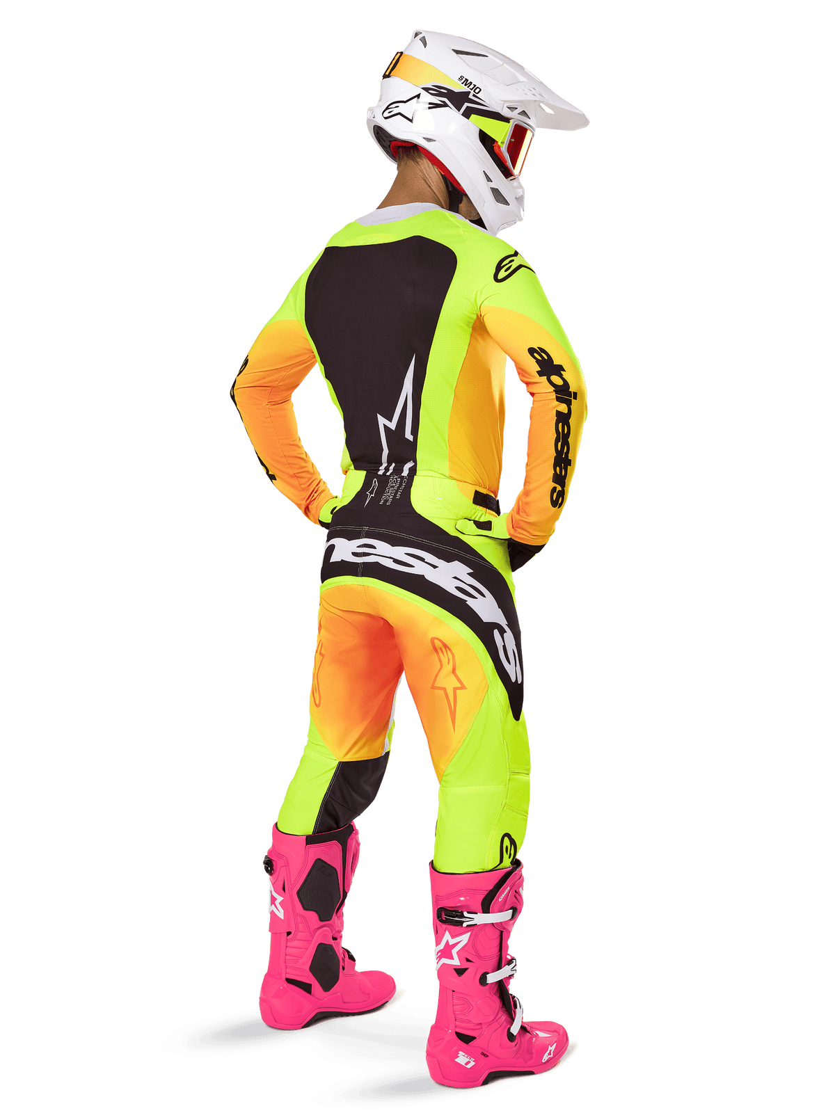 Pilota di motocross visto da dietro con il completo Alpinestars 2025 Techstar Melt, maglia e pantaloni con sfumatura giallo e arancione e pannelli neri, casco bianco con occhiali rossi e stivali rosa acceso, abbigliamento da corsa coordinato per prestazioni fuoristrada