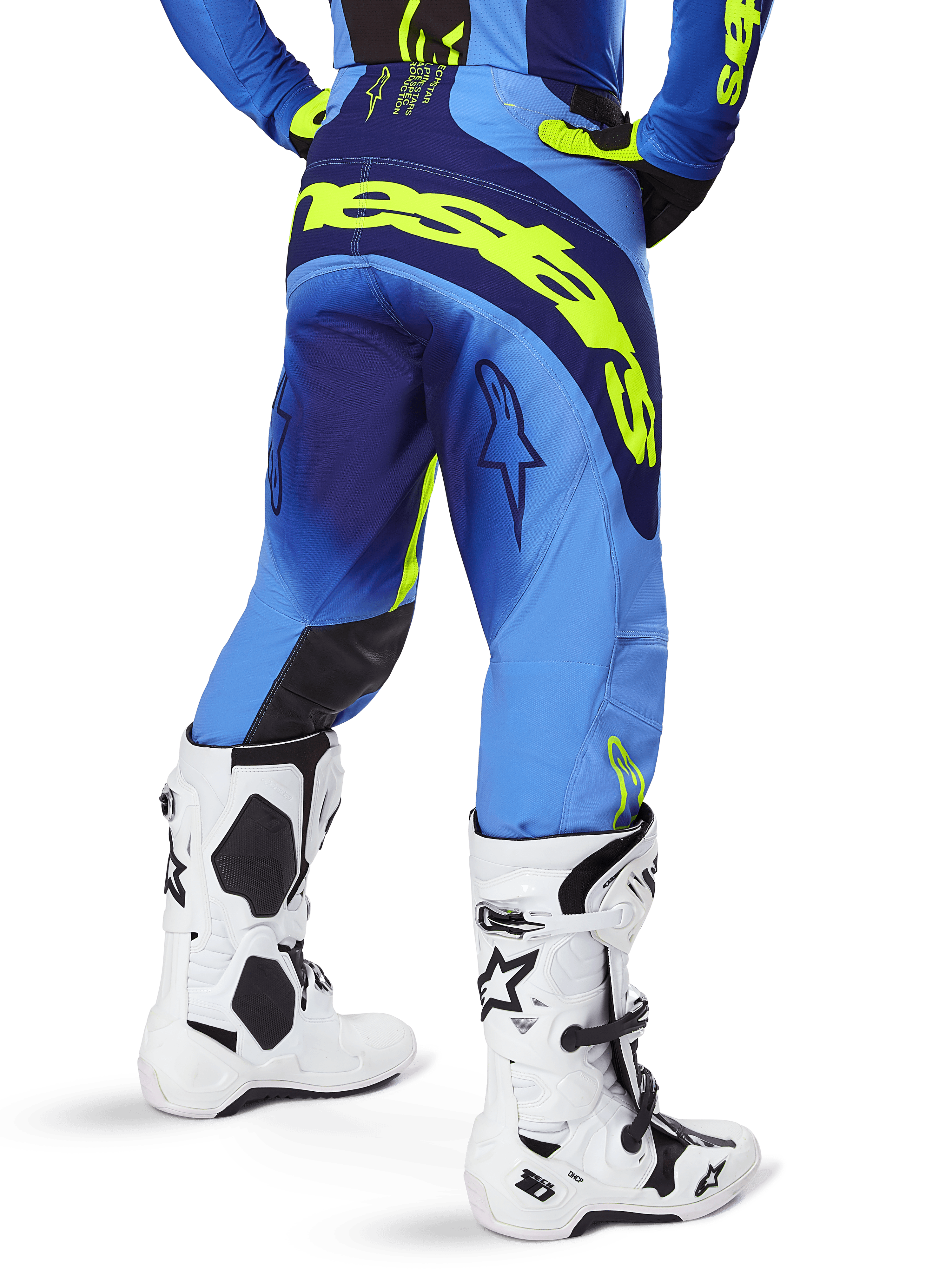 Alpinestars 2025 Techstar Melt Pants, pantaloni da motocross, blu e giallo fluo, vista posteriore con grande marchio giallo sulla seduta e sulle cosce, indossati con stivali da motocross bianchi e maglia blu coordinata, vestibilità atletica da gara per fuoristrada