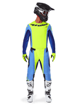 Alpinestars 2025 Techstar Melt Pants, pantaloni da motocross, giallo fluo e blu, indossati con maglia coordinata, guanti gialli e stivali bianchi e neri, con casco nero e maschera rossa, set completo di abbigliamento da gara per prestazioni fuoristrada