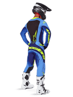 Alpinestars 2025 Techstar Melt Pants, equipaggiamento da motocross, Giallo Fluo Blu, vista posteriore del pilota che indossa una maglia blu coordinata con grande logo giallo, stivali bianchi e neri e casco nero, completo da gara coordinato per prestazioni fuoristrada