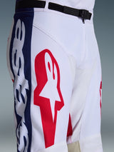 Pantaloni Alpinestars Racer Riway 2026, pantaloni da motocross, bianco blu rosso, primo piano della parte superiore della gamba e della vita che mostra il grande logo a stella rosso su tessuto bianco, pannelli laterali blu con marchio e cintura regolabile nera in vita con fibbia magnetica SX2, design sportivo da corsa fuoristrada
