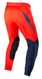 Alpinestars Supertech Blaze Pants, pantaloni da motocross, rosso acceso e blu scuro, vista posteriore di tre quarti, con logo ASTARS blu scuro sul lato, pannelli rinforzati neri sulle ginocchia e vestibilità atletica per prestazioni fuoristrada