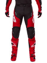 Alpinestars Racer Veil 2025, pantaloni da motocross, nero e rosso brillante, indossati con guanti e stivali rossi coordinati, grandi loghi Alpinestars bianchi sulle cosce, pannelli neri sulle ginocchia e fibbia regolabile in vita per la guida off-road