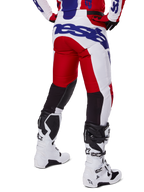 Alpinestars 2025 Racer Veil Pants, pantaloni da motocross, rosso acceso e bianco con logo blu, vista posteriore che mostra i pannelli di ventilazione neri sul retro delle gambe, abbinati a stivali da motocross bianchi