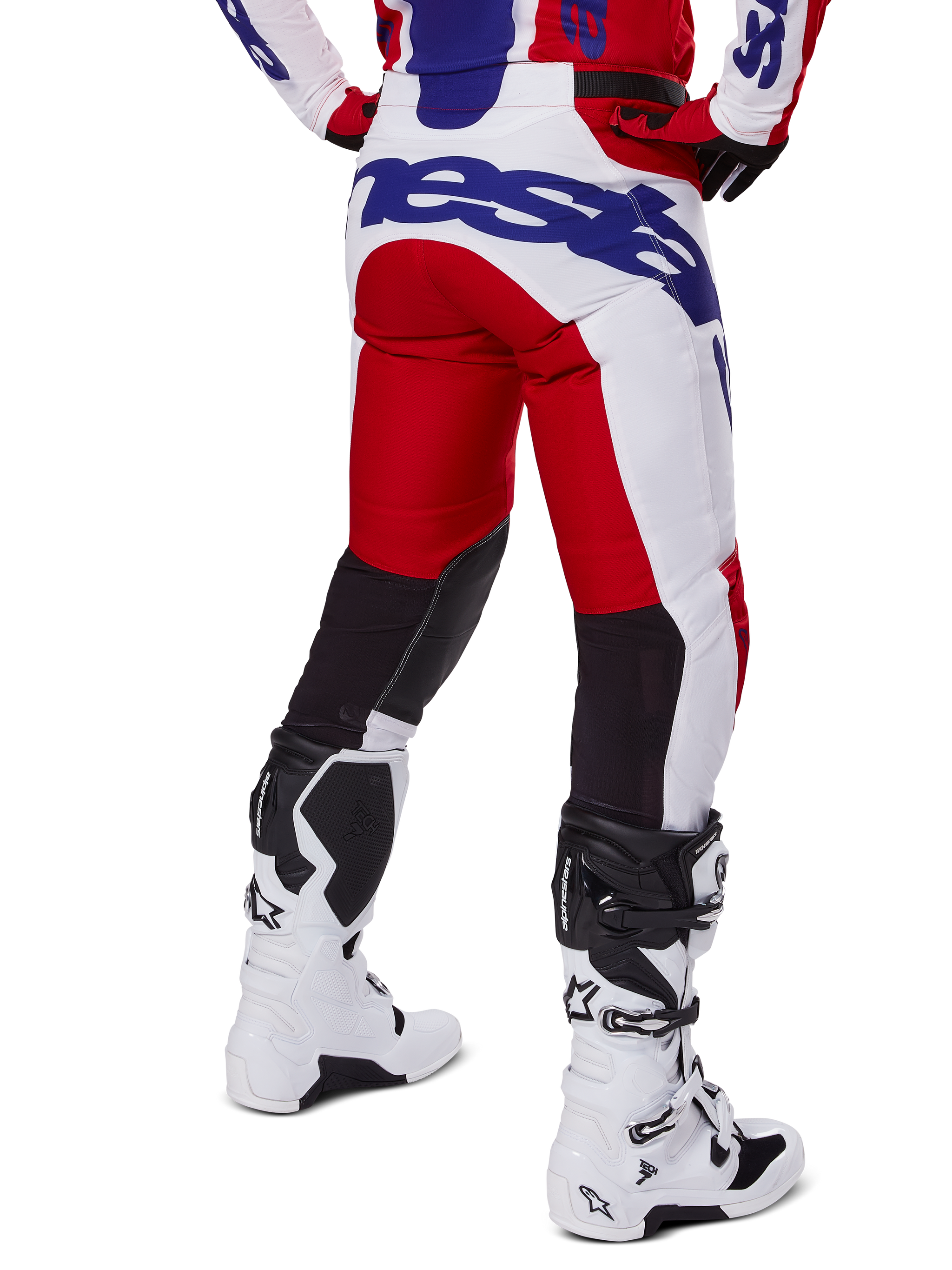 Alpinestars 2025 Racer Veil Pants, pantaloni da motocross, rosso acceso e bianco con logo blu, vista posteriore che mostra i pannelli di ventilazione neri sul retro delle gambe, abbinati a stivali da motocross bianchi