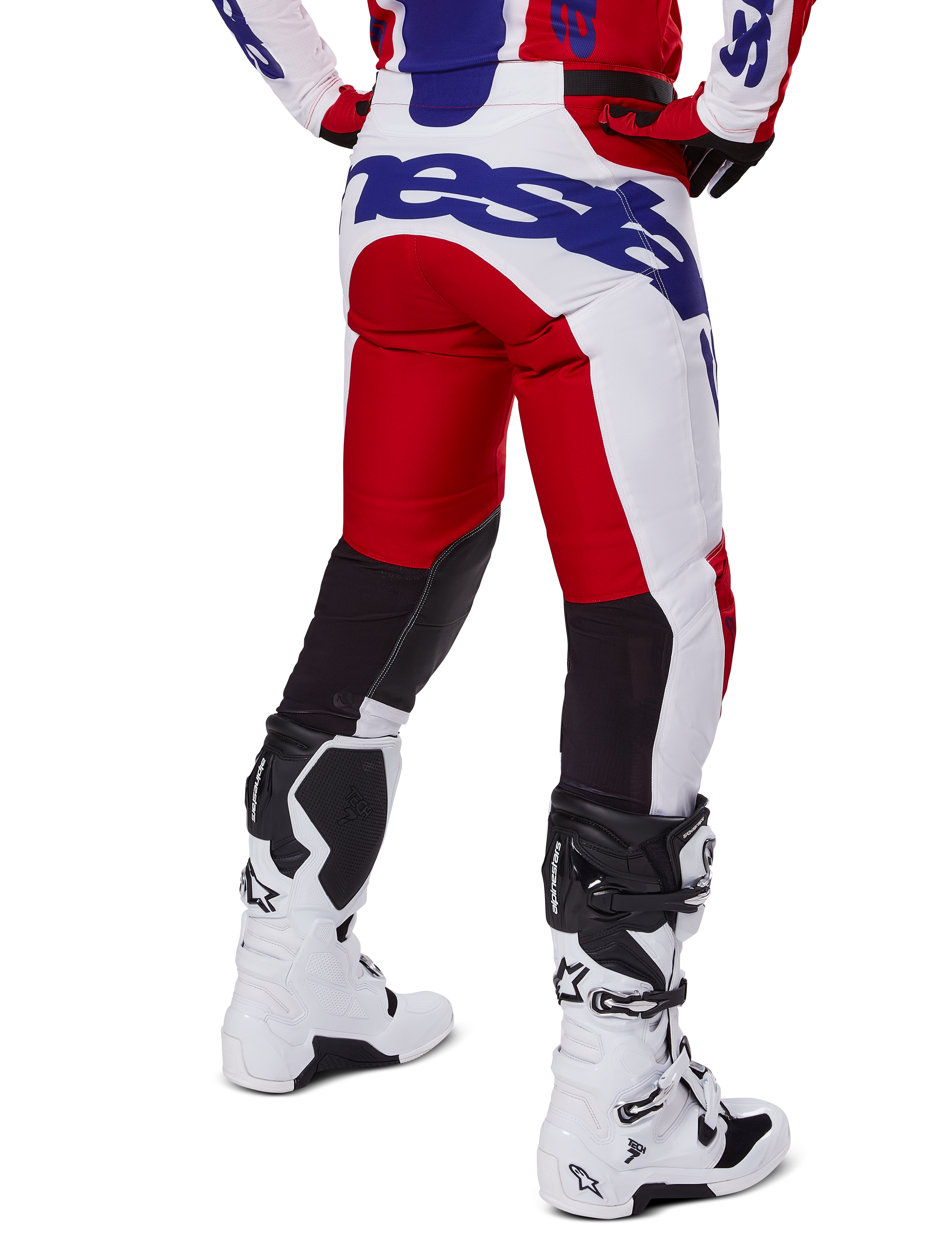 Alpinestars 2025 Racer Veil Pants, pantaloni da motocross, rosso acceso e bianco con logo blu, vista posteriore che mostra i pannelli di ventilazione neri sul retro delle gambe, abbinati a stivali da motocross bianchi