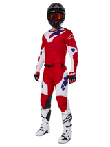 Alpinestars 2025 Racer Veil Pants, pantaloni da motocross, rosso acceso e bianco, indossati come parte di un set completo da gara con maglia coordinata rossa e bianca, casco nero con occhiali arancioni, stivali bianchi e guanti rossi, con loghi Alpinestars blu vivace.
