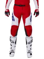 Alpinestars 2025 Racer Veil Pants, pantaloni da motocross, rosso acceso e bianco, indossati con guanti rossi abbinati e stivali bianchi, con branding blu sulle cosce e cintura nera in vita, taglio sportivo ergonomico per prestazioni elevate