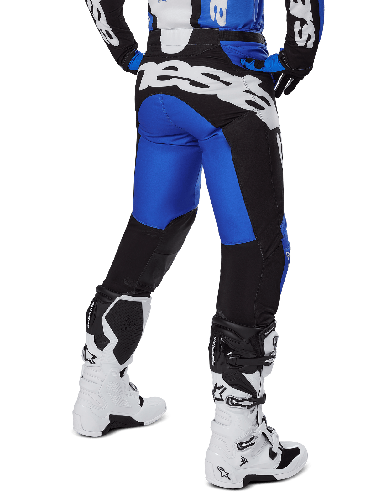 Pantaloni Alpinestars Racer Veil 2025, pantaloni da motocross, blu e nero, vista posteriore con grande marchio bianco sulla seduta, indossati con maglia coordinata e stivali bianchi, materiale tecnico resistente per il fuoristrada