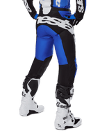 Pantaloni Alpinestars Racer Veil 2025, pantaloni da motocross, blu e nero, vista posteriore con grande marchio bianco sulla seduta, indossati con maglia coordinata e stivali bianchi, materiale tecnico resistente per il fuoristrada