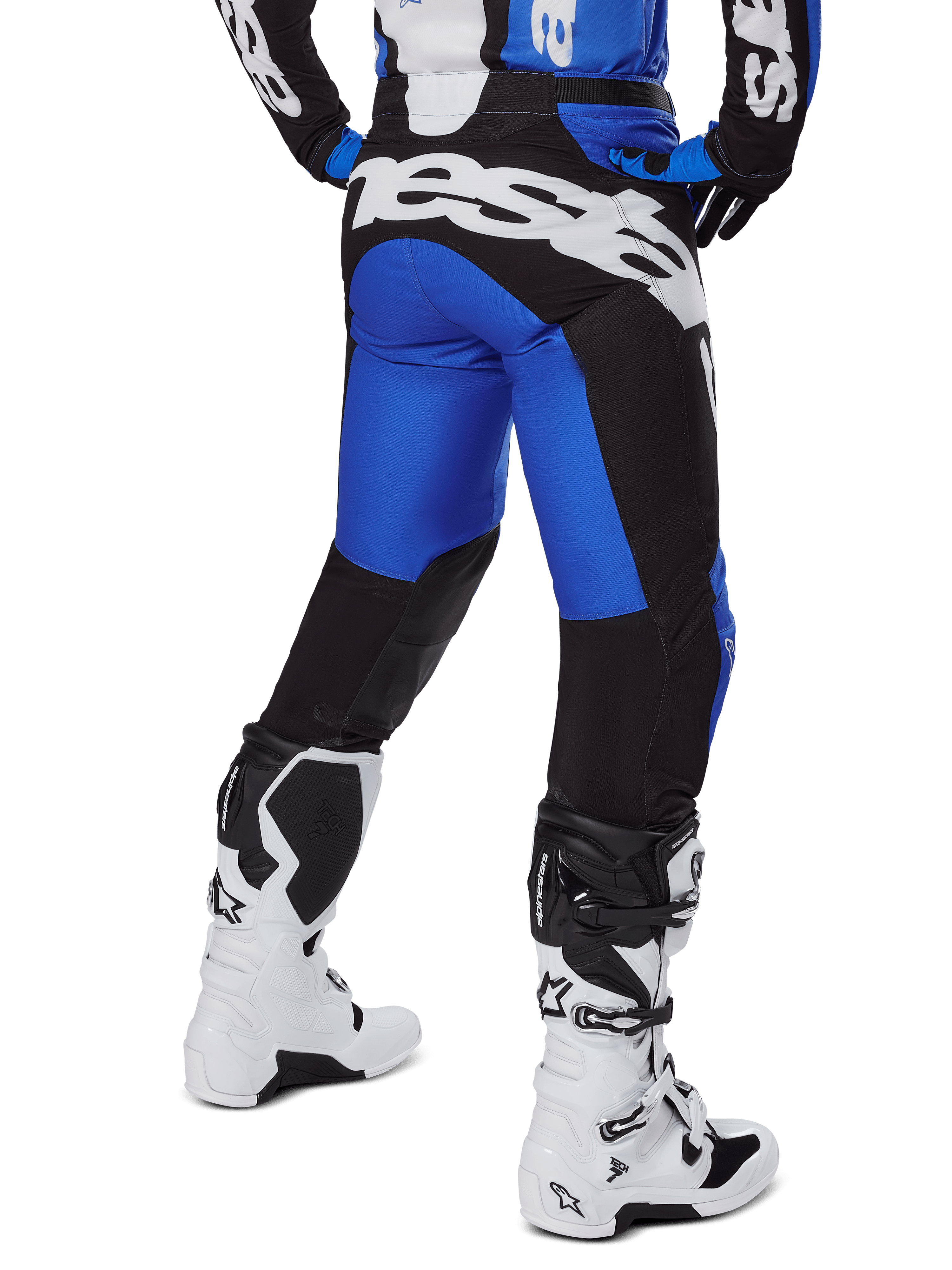 Pantaloni Alpinestars Racer Veil 2025, pantaloni da motocross, blu e nero, vista posteriore con grande marchio bianco sulla seduta, indossati con maglia coordinata e stivali bianchi, materiale tecnico resistente per il fuoristrada