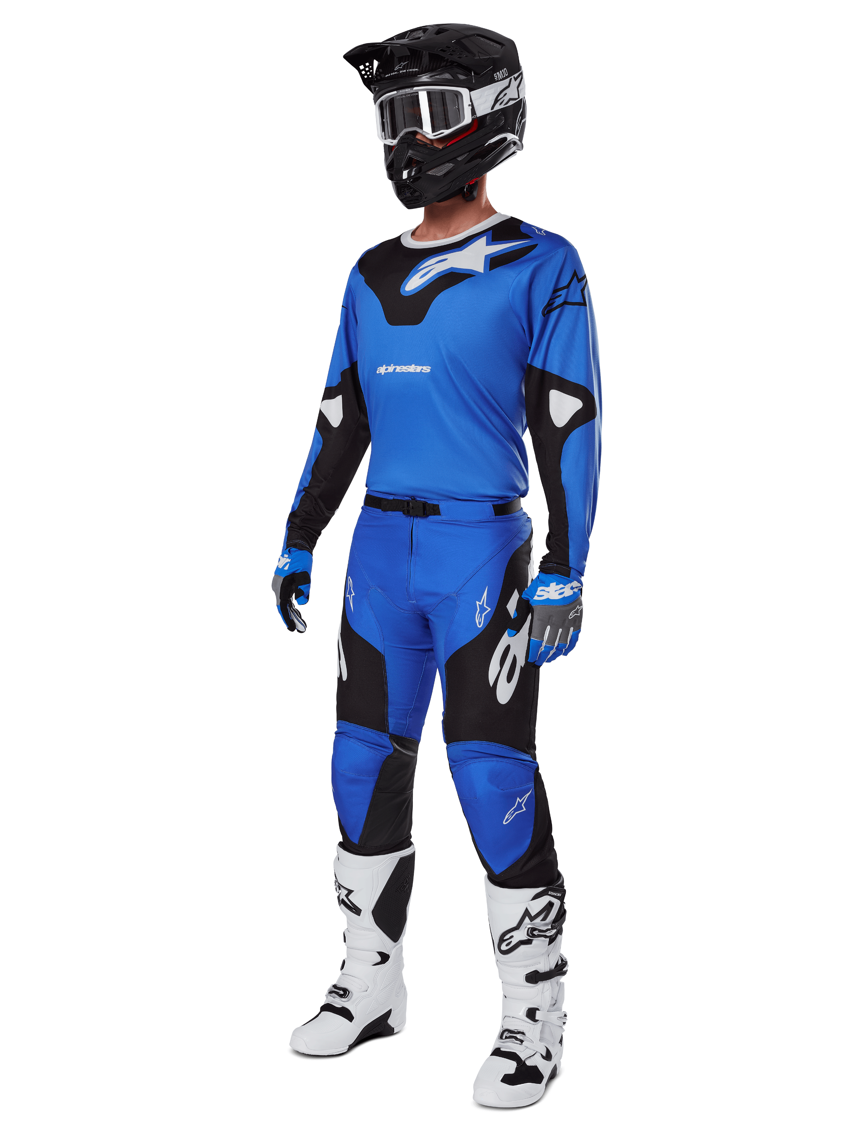Pilota di motocross con abbigliamento da gara completo, inclusi pantaloni Alpinestars Racer Veil 2025 blu e neri, maglia blu coordinata con dettagli bianchi, casco nero con occhiali bianchi, stivali bianchi e neri e guanti blu, completo coordinato per gare off-road