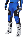 Alpinestars 2025 Racer Veil Pants, pantaloni da motocross, blu e nero con dettagli grafici bianchi, indossati con maglia e guanti blu coordinati e stivali bianchi, attrezzatura protettiva resistente per gare fuoristrada