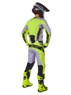 Pantaloni Alpinestars Racer Veil 2025, pantaloni da motocross, grigio e giallo fluo, vista posteriore del pilota con equipaggiamento completo, maglia coordinata e stivali giallo fluo, con loghi neri marcati, kit tecnico da gara fuoristrada.