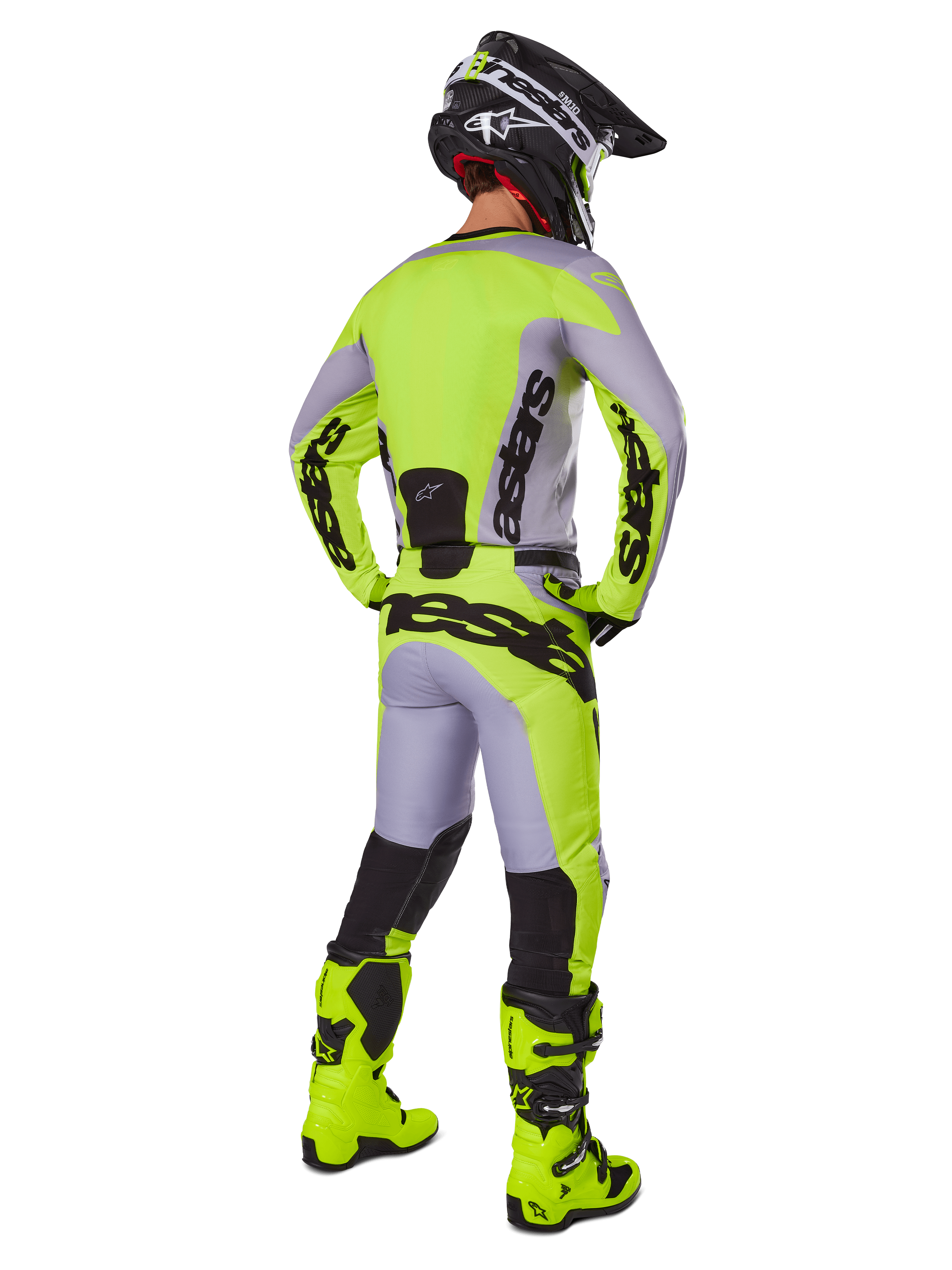 Pantaloni Alpinestars Racer Veil 2025, pantaloni da motocross, grigio e giallo fluo, vista posteriore del pilota con equipaggiamento completo, maglia coordinata e stivali giallo fluo, con loghi neri marcati, kit tecnico da gara fuoristrada.