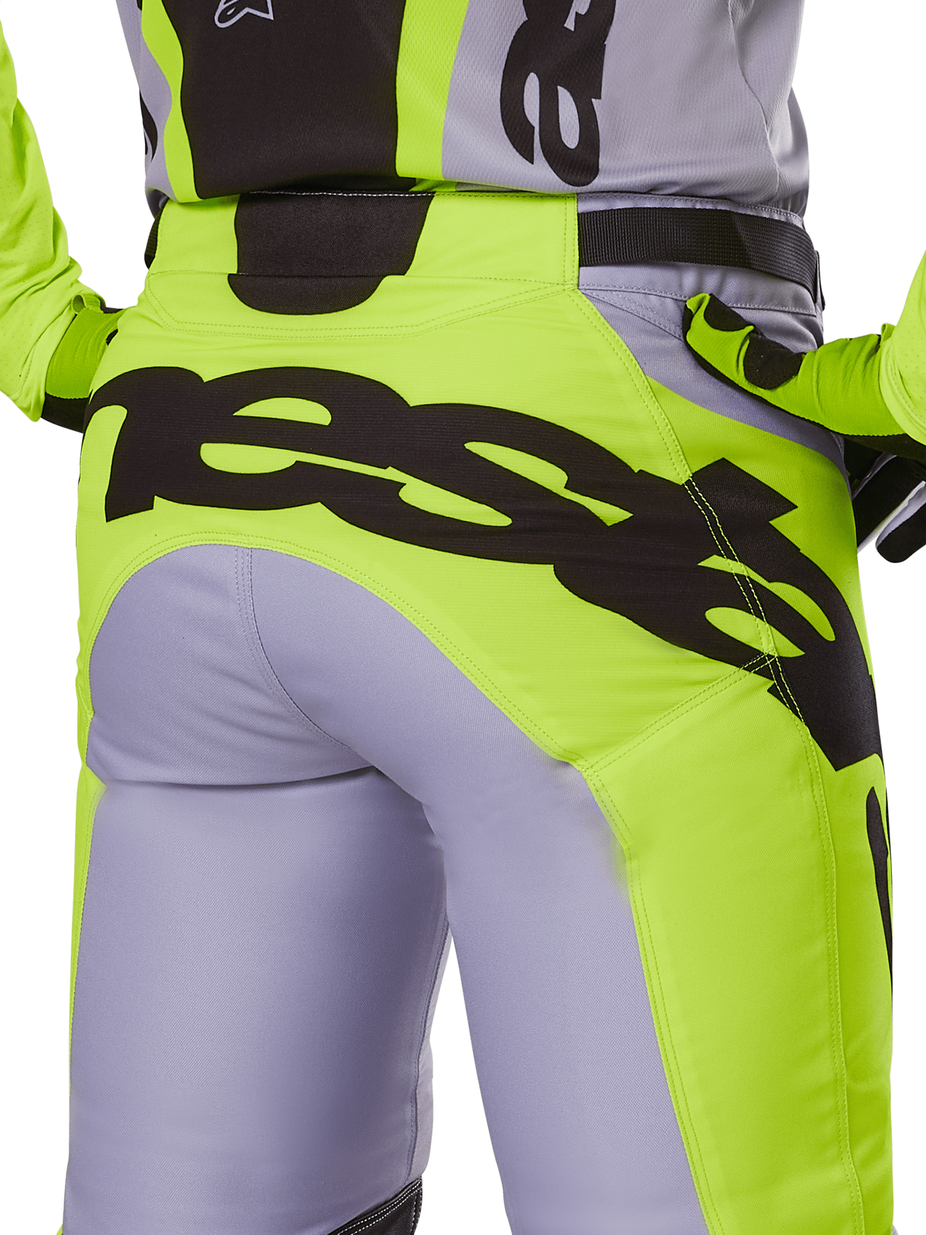 Alpinestars Pantaloni Racer Veil 2025, pantaloni da motocross, grigio e giallo fluo, vista posteriore con grande logo nero sulla seduta, indossati con maglia e guanti coordinati, design tecnico per fuoristrada