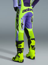 Alpinestars pantaloni Racer Portl 2026, pantaloni da motocross, viola e giallo fluo, vista posteriore con marchio astars e dettagli viola, indossati con stivali da motocross giallo fluo coordinati, materiale sintetico resistente per gare off-road