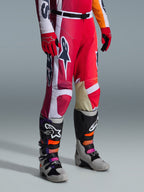 Pantaloni Alpinestars 2026 Racer Portl, pantaloni da motocross, rosso, grigio chiaro e grigio scuro, indossati con guanti rossi coordinati e stivali da motocross multicolore, con loghi Alpinestars e pannelli rinforzati per corse off-road.