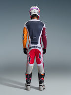 Pilota di motocross visto da dietro che indossa i pantaloni 2026 Racer Portl in rosso, grigio chiaro e grigio scuro, con il marchio "astars" sulla parte posteriore, coordinati con una maglia multicolore, casco bianco e stivali da corsa tecnici.