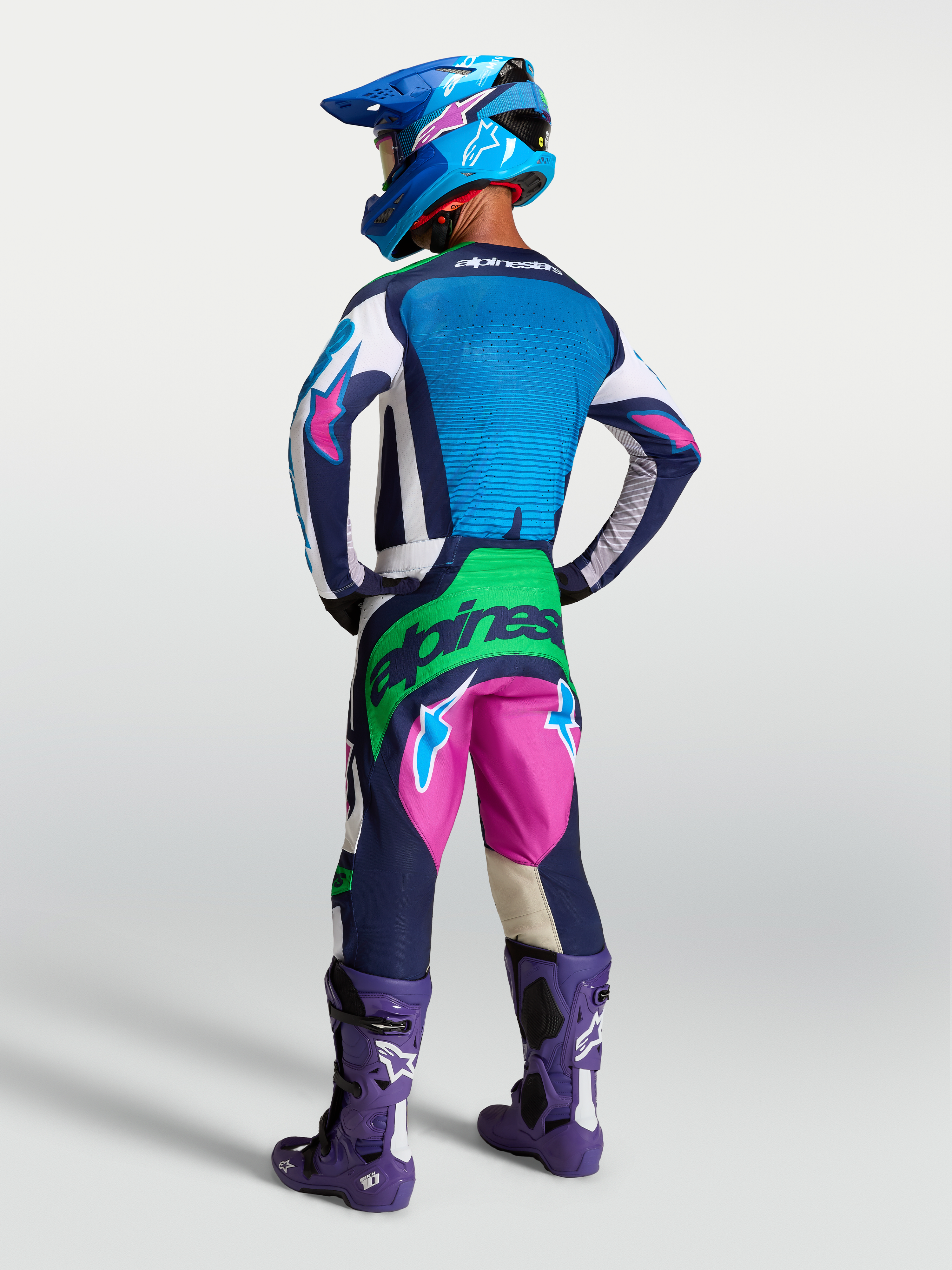 Alpinestars Techstar Maven Gear Set e Pantaloni, completo da motocross blu e rosa con accenti verde fluo, vista posteriore.