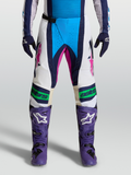 Alpinestars Pantaloni Techstar Maven, pantaloni motocross bianco e blu con dettagli rosa, costruzione del ginocchio Babel 3D, indossati da modella, frontale.