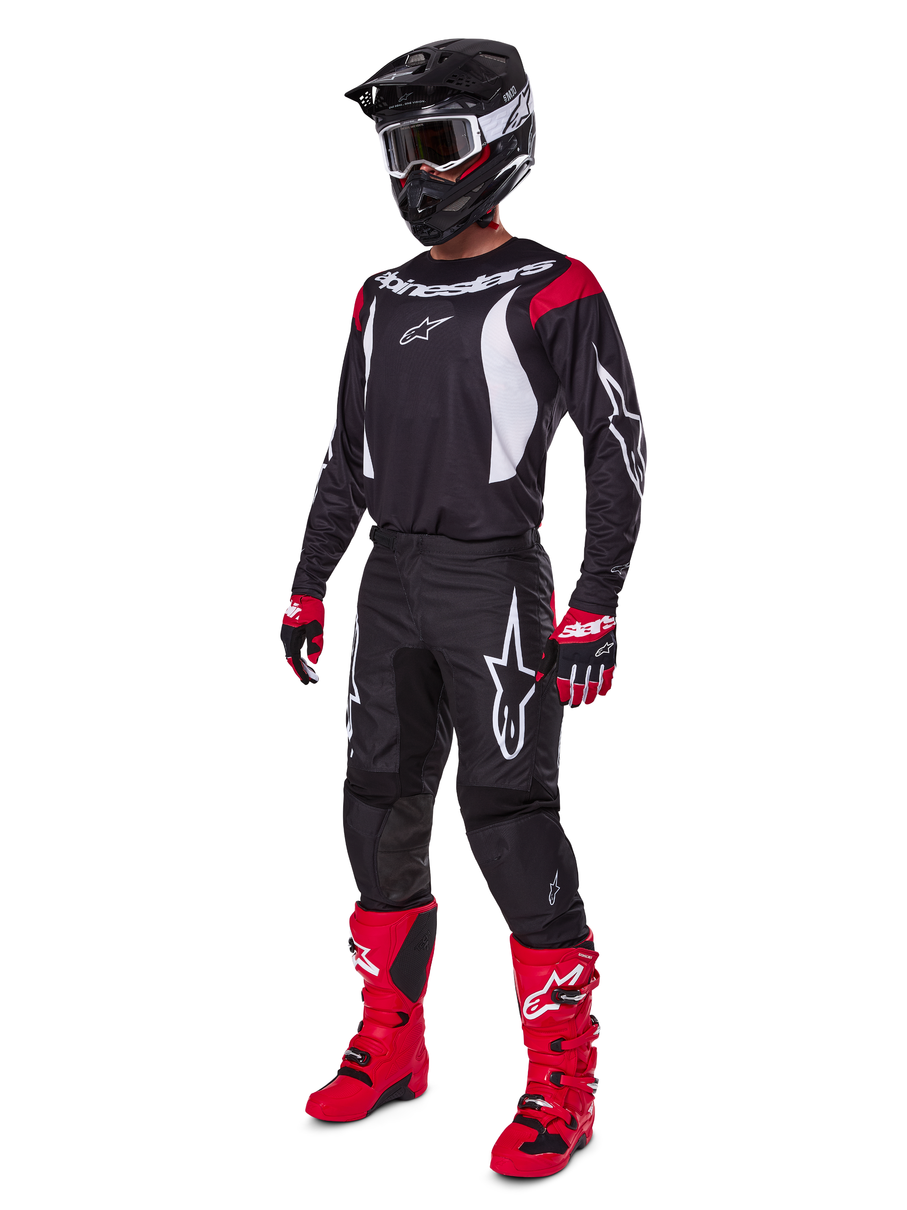 Pilota da motocross con set completo Alpinestars 2025 Fluid Haul, maglia nera con dettagli rossi e bianchi, pantaloni neri con loghi bianchi, stivali rosso acceso, guanti rossi e neri, casco nero con maschera, abbigliamento tecnico coordinato per fuoristrada