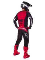 Pilota di motocross con il Set Gear Alpinestars 2025 Fluid Haul visto da dietro, maglia rossa e nera con logo bianco, pantaloni neri coordinati con accenti rossi, stivali rosso acceso e casco nero con occhiali bianchi, outfit completo coordinato per gare off-road