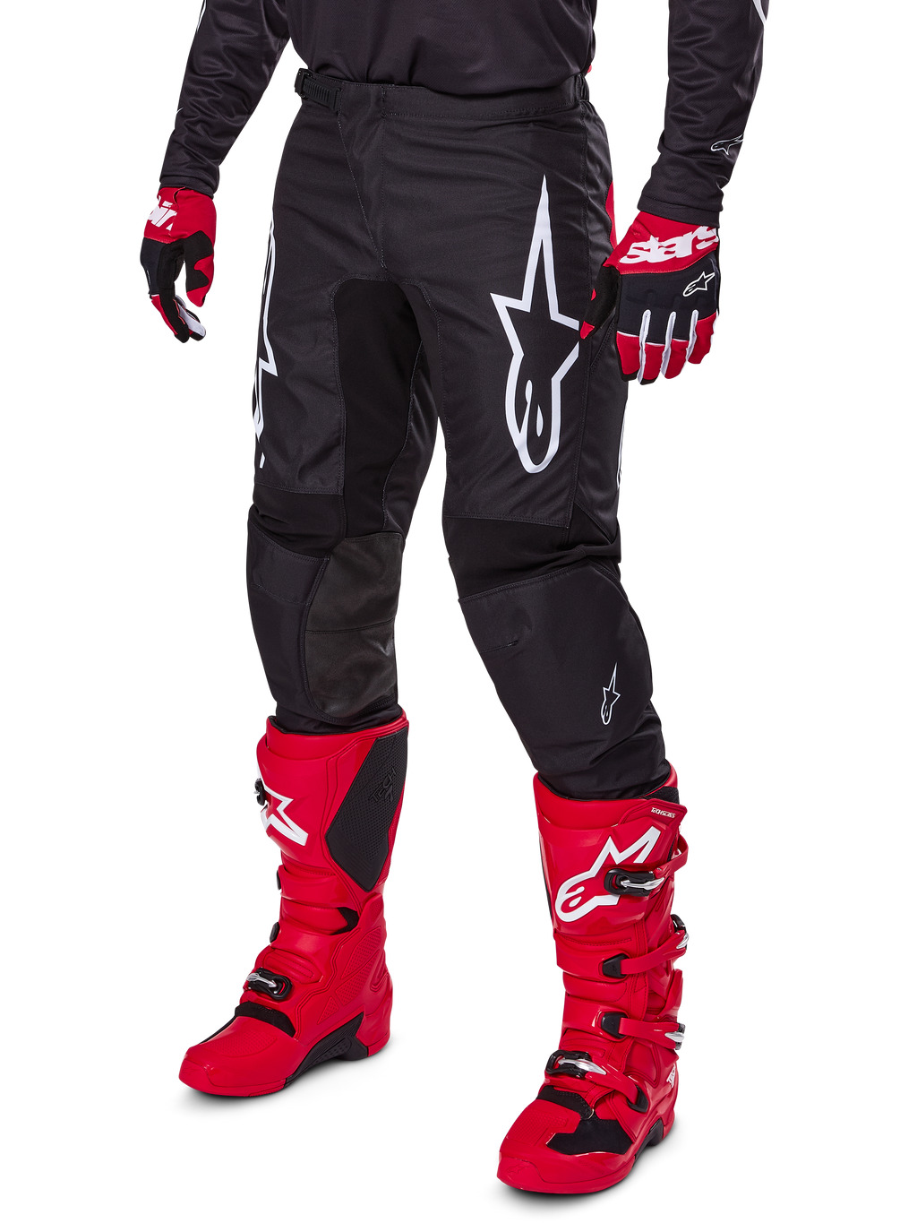 Alpinestars 2025 Fluid Haul Pants, pantaloni da motocross, nero, con un grande logo Alpinestars bianco, indossati con stivali rosso acceso e guanti rossi e neri, costruzione resistente in poliestere 600D con taglio ergonomico per il fuoristrada
