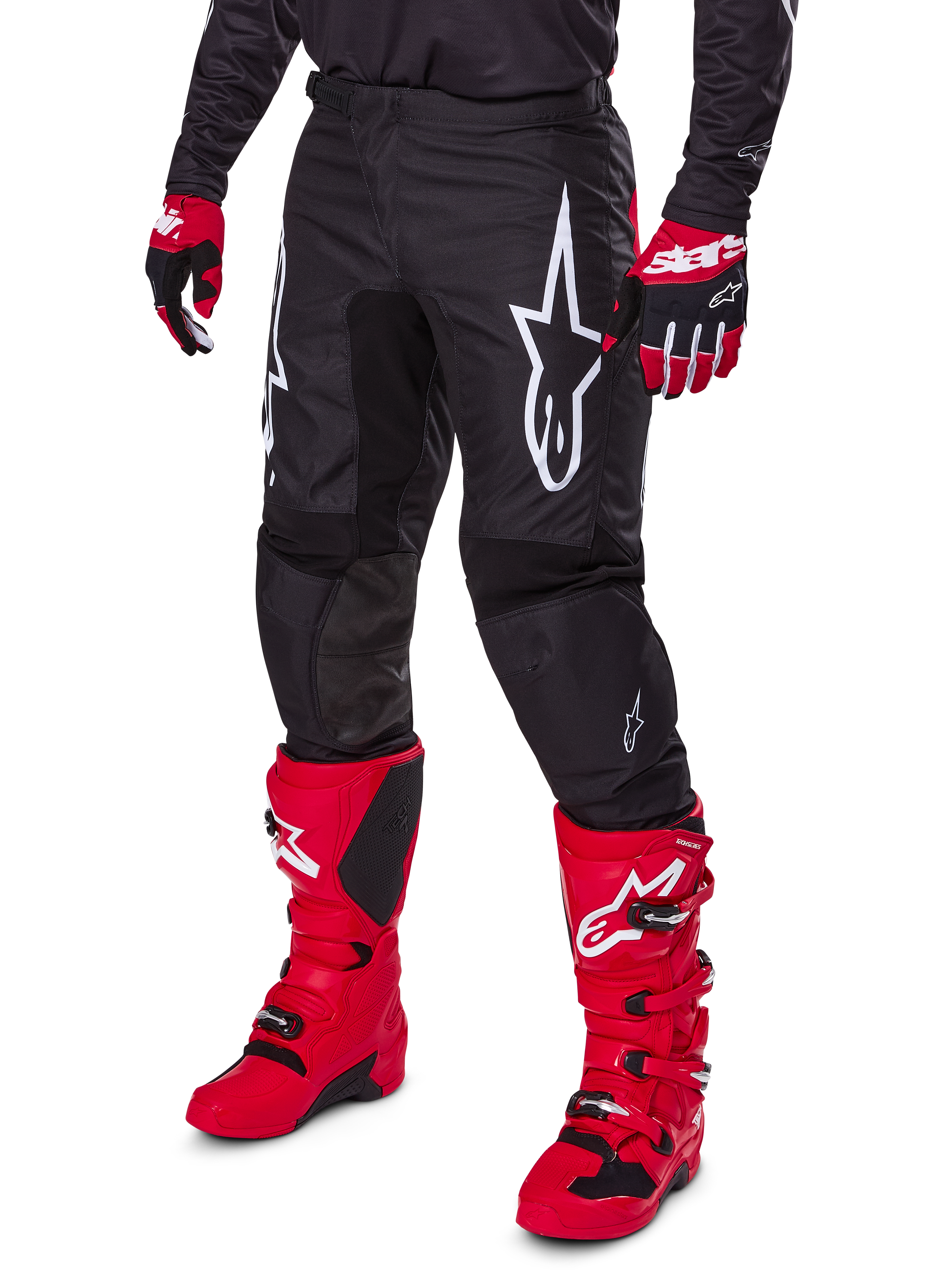Alpinestars 2025 Fluid Haul Pants, pantaloni da motocross, nero, con un grande logo Alpinestars bianco, indossati con stivali rosso acceso e guanti rossi e neri, costruzione resistente in poliestere 600D con taglio ergonomico per il fuoristrada