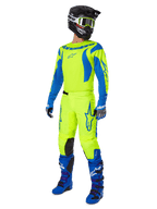 Alpinestars 2025 Fluid Haul Pants, pantaloni da motocross, giallo fluo e blu, indossati come parte di un set completo da gara con maglia coordinata, stivali blu e casco nero, design ad alta visibilità per la guida fuoristrada