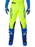 Alpinestars 2025 Fluid Haul Pants, pantaloni da motocross, giallo brillante e blu, indossati con guanti e stivali coordinati, con pannelli interni neri sulle ginocchia, loghi blu sulle cosce e design sportivo ergonomico.