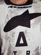 Alpinestars 2026 Racer Lahnd Jersey, primo piano dell'area del torace, motivo Sand Camo con grande logo a stella nero e scritta Alpinestars, poliestere tecnico traspirante per la guida fuoristrada