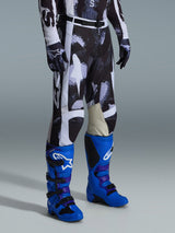 Pantaloni Alpinestars Racer Lahnd 2026, pantaloni da motocross, motivo mimetico Iron Camo grigio e nero, abbinati a stivali da gara blu acceso e guanti coordinati, con pannelli bianchi e interno ginocchia in pelle di capra, abbigliamento off-road ad alte prestazioni