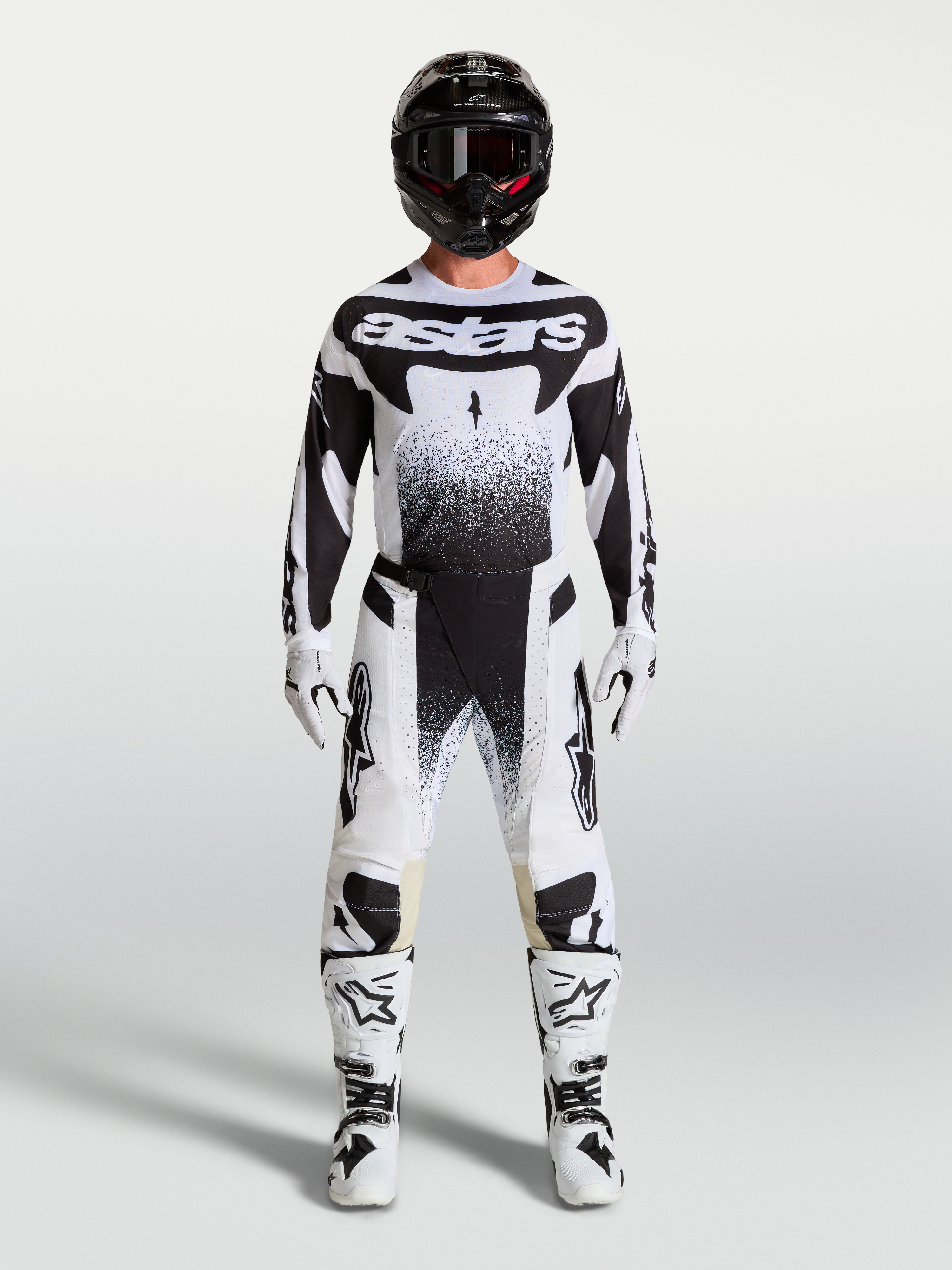 Alpinestars Pantaloni Techstar Swan e maglia, completo da motocross bianco e nero con stivali e casco coordinati su un modello, abbigliamento tecnico off-road.