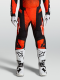 Alpinestars 2027 Techstar Swan Motocross Pants in cardinal red and black, styled with white racing boots and gloves.