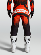 Alpinestars Pantaloni Techstar Swan, pantaloni da motocross rossi e neri, vista posteriore con logo bianco e stivali bianchi