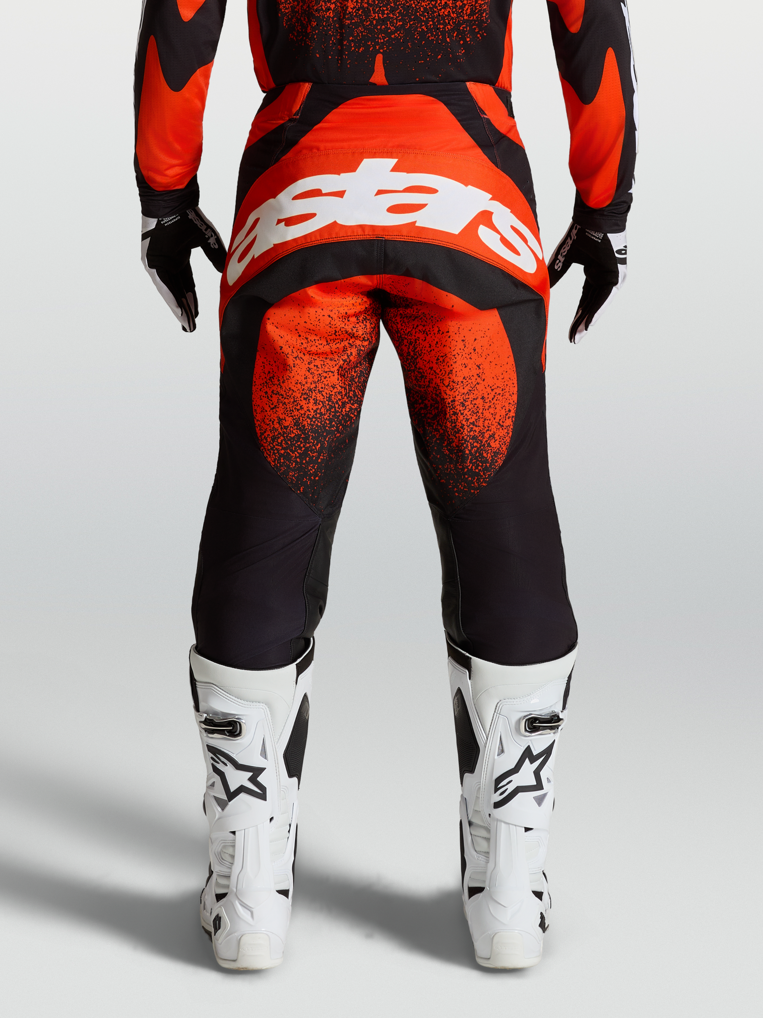 Alpinestars Pantaloni Techstar Swan, pantaloni da motocross rossi e neri, vista posteriore con logo bianco e stivali bianchi