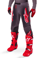 Set Alpinestars Supertech Lipan 2025, pantaloni da motocross grigi con vivaci loghi a stella rossi e bianchi, abbinati a stivali da performance rosso acceso e guanti rossi e neri, progettati per gare di livello professionale