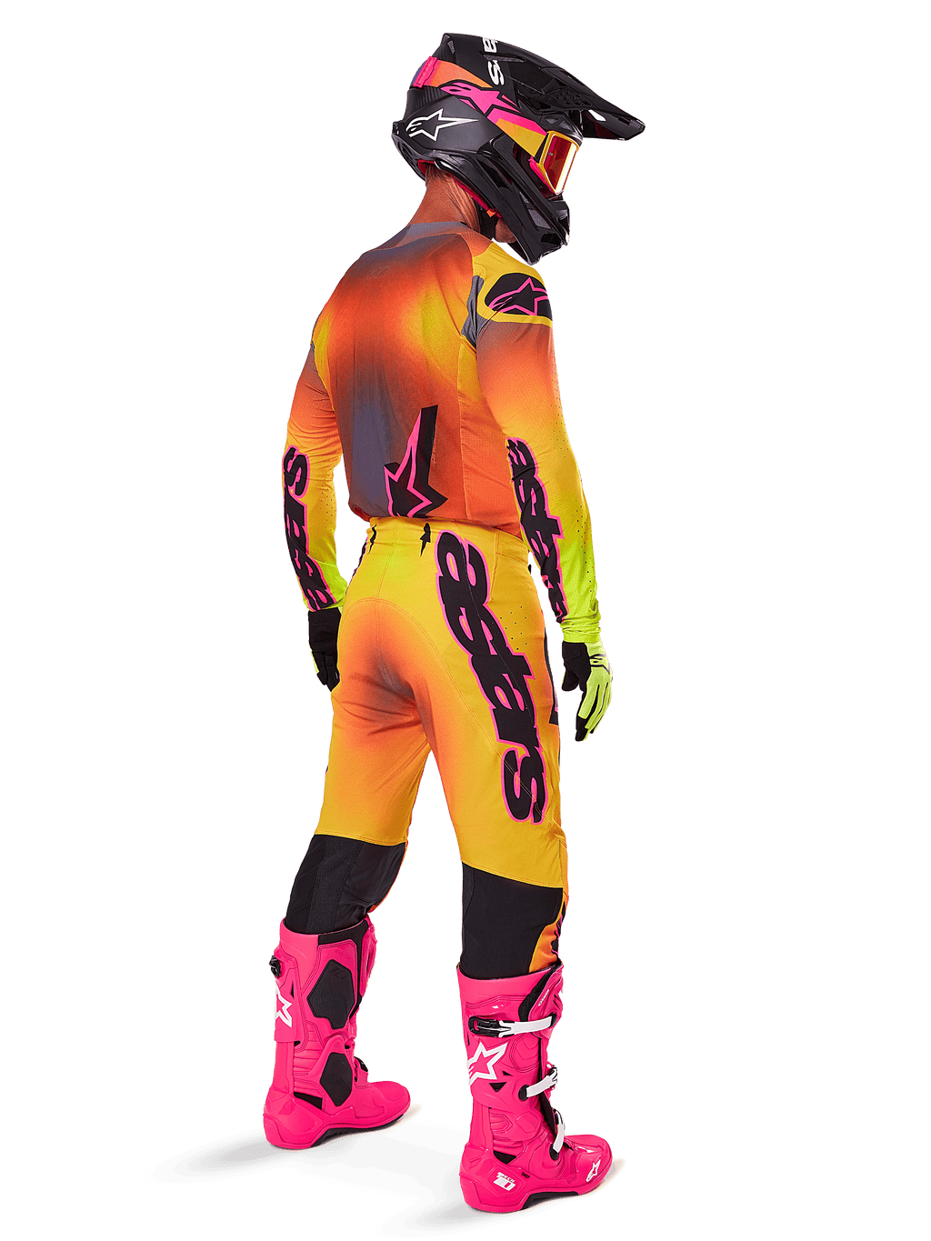 Pilota di motocross visto da dietro, pantaloni Alpinestars 2025 Supertech Lipan con sfumatura giallo e rosa, maglia coordinata, stivali rosa acceso e casco nero con accenti rosa, completo professionale per gare off-road