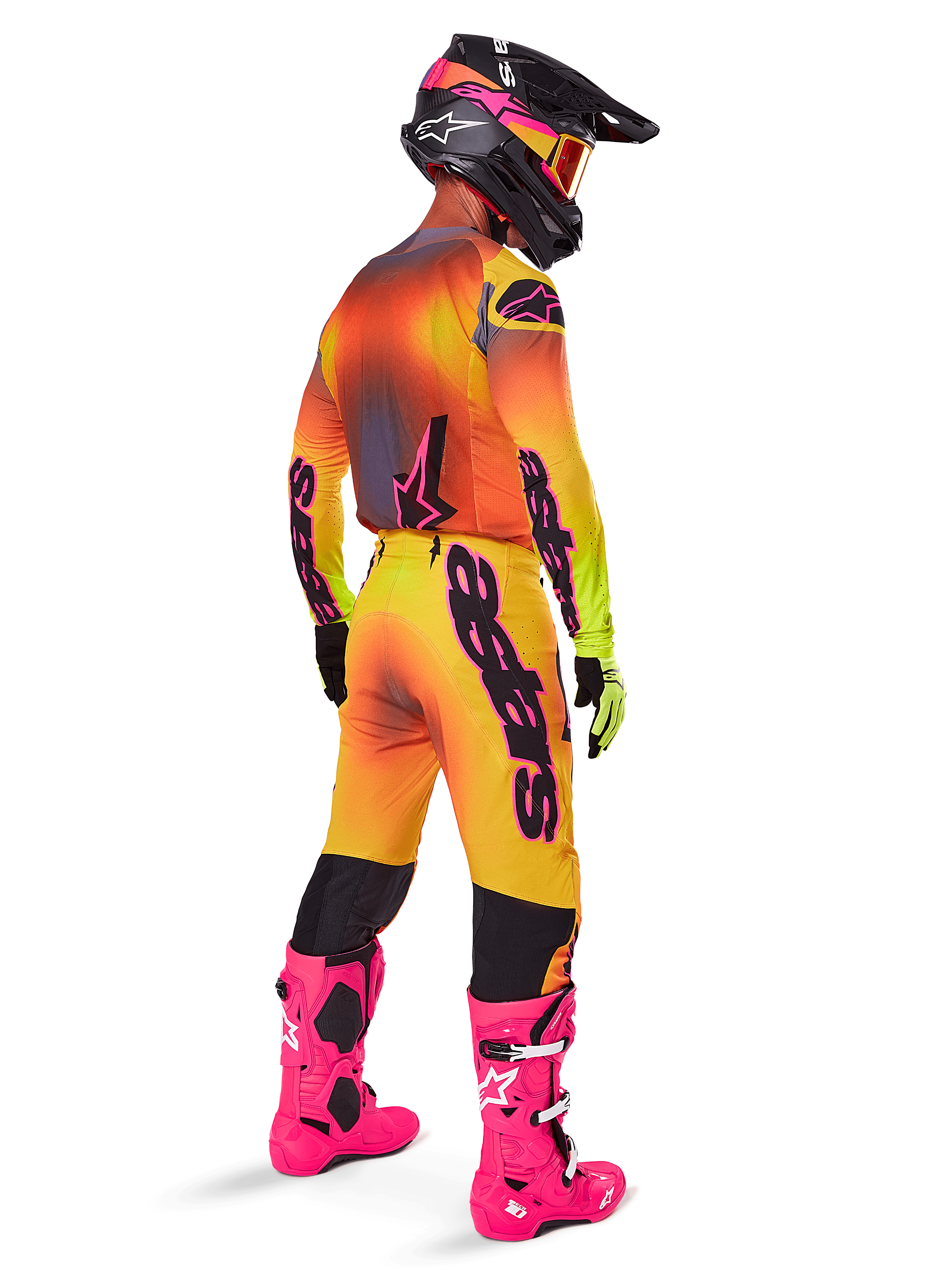 Pilota di motocross visto da dietro, pantaloni Alpinestars 2025 Supertech Lipan con sfumatura giallo e rosa, maglia coordinata, stivali rosa acceso e casco nero con accenti rosa, completo professionale per gare off-road
