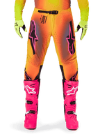 Pantaloni Alpinestars Supertech Lipan 2025, pantaloni da motocross, sfumatura arancione e gialla con accenti rosa e neri, indossati con stivali rosa acceso e guanti giallo neon, dotati di ventilazione tagliata al laser e fibbia sicura in vita, completo da gara professionale