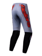 Alpinestars Pantaloni Supertech Lipan 2025, pantaloni da motocross, grigio e arancione fluo, vista posteriore con pannelli neri sulla parte inferiore della gamba e grandi grafiche del logo Alpinestars arancioni sui fianchi, vestibilità atletica per gare fuoristrada
