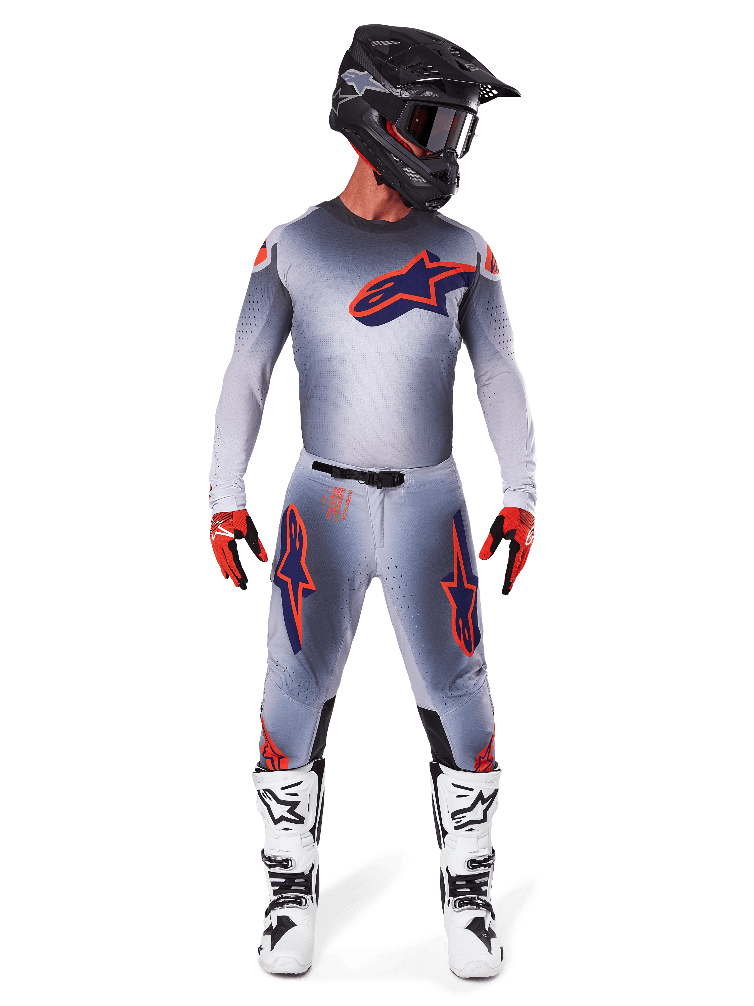 Pilota di motocross con pantaloni Alpinestars Supertech Lipan 2025 e maglia coordinata in Grigio Arancione Fluo, con loghi arancioni e blu navy, abbinati a casco nero, guanti rossi e stivali bianchi e neri, kit da gara completo per prestazioni fuoristrada