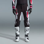 Alpinestars 2026 Supertech AFD Vista Gear Set, pilota di motocross con pantaloni neri e grandi loghi bianchi e rossi, maglia tecnica coordinata con polsini bordeaux, guanti neri e stivali da gara professionali bianchi, completo da gara fuoristrada ad alte prestazioni