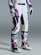 Alpinestars 2026 Supertech AFD Vista Pants, pantaloni da motocross, bianco, viola e nero, con logo Astar sfumato rosa e viola, indossati con stivali e guanti da motocross bianchi e viola coordinati, vestibilità atletica race con pannelli interni al ginocchio in pelle beige e dettagli traforati.