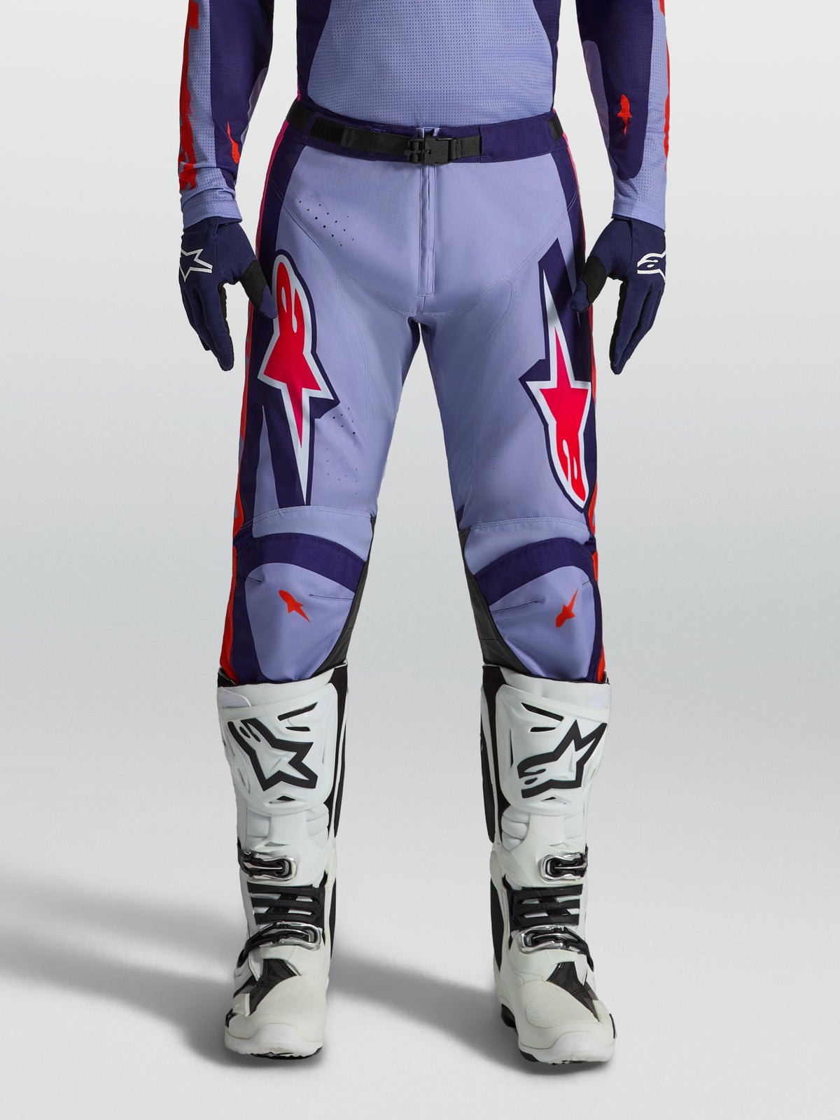 Alpinestars pantaloni Racer Air Hunt, pantaloni da motocross uomo viola e rosa fluo, indossati con stivali bianchi.
