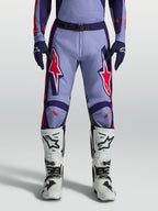 Alpinestars pantaloni Racer Air Hunt, pantaloni da motocross uomo viola e rosa fluo, indossati con stivali bianchi.