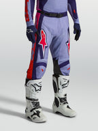 Alpinestars Pantaloni Racer Air Hunt, pantaloni da motocross da uomo viola e rosa ventilati, mostrati con stivali bianchi