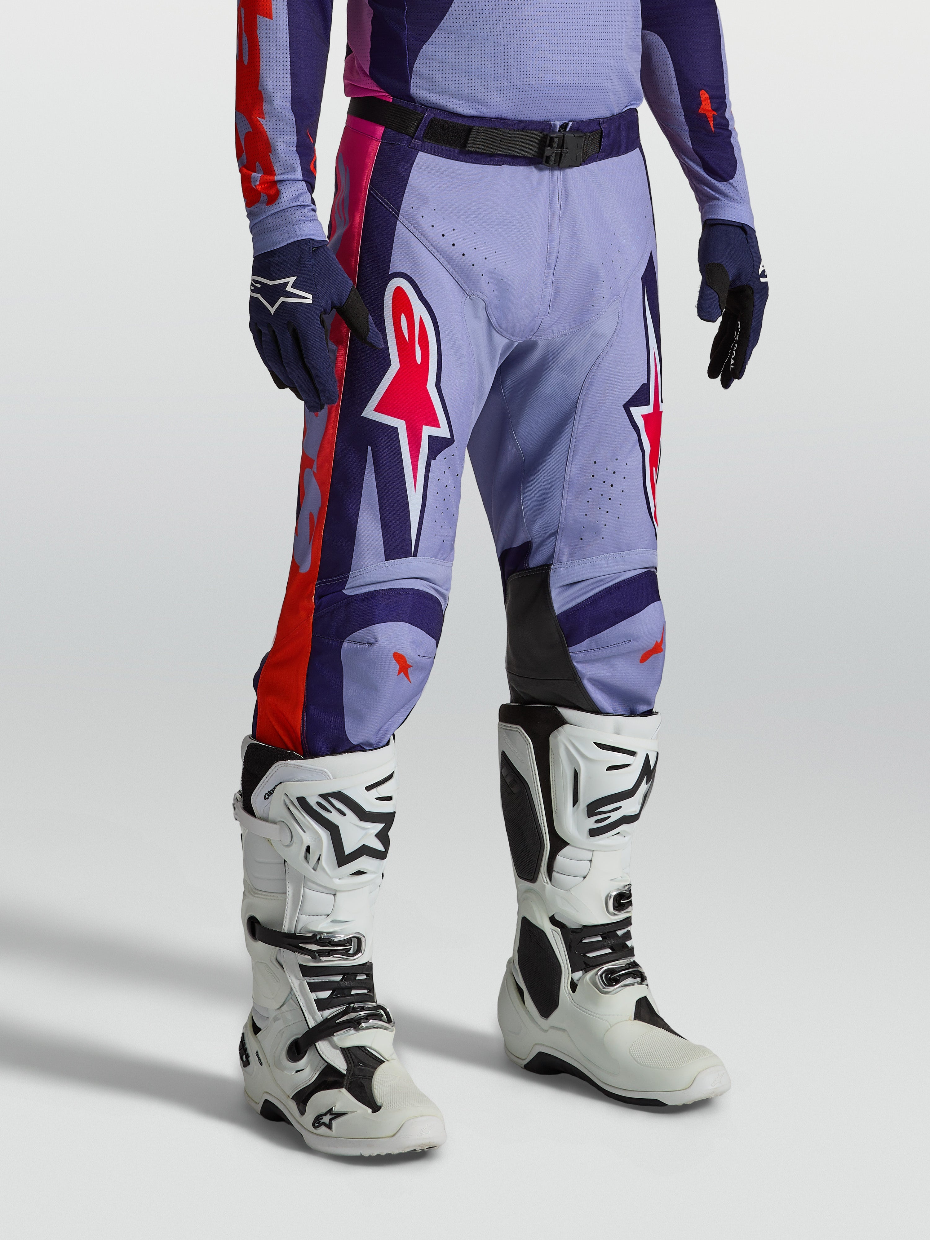 Alpinestars Pantaloni Racer Air Hunt, pantaloni da motocross da uomo viola e rosa ventilati, mostrati con stivali bianchi