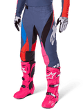 Alpinestars 2025 Techstar Dreem Pants, pantaloni da motocross, grigio scuro con sezioni blu, rosso e rosa, grafiche bianche, indossati con stivali rosa brillante e guanti bianco e nero, design audace ad alta visibilità
